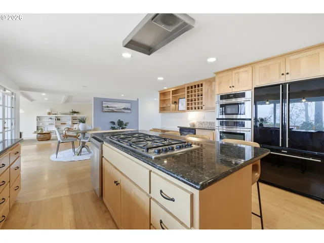 a open kitchen with stainless steel appliances kitchen island granite countertop a refrigerator a stove and a sink with wooden floor