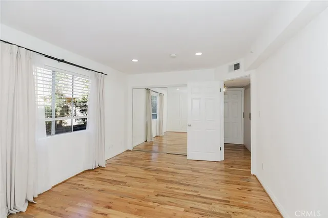 a view of empty room with wooden floor and fan