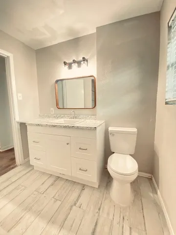 a bathroom with a granite countertop toilet a sink and a mirror