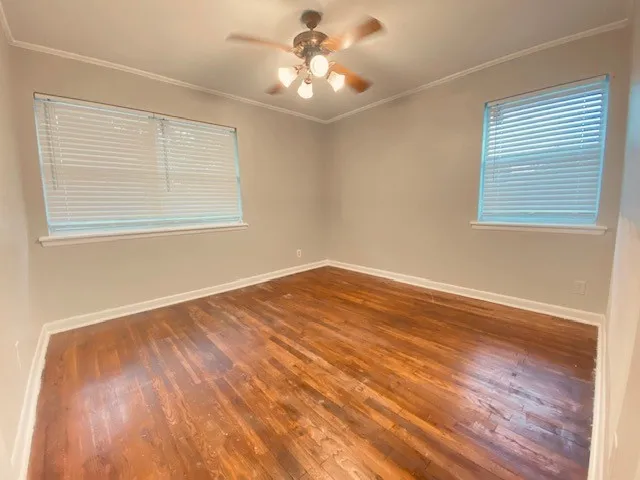 a view of empty room with wooden floor and fan