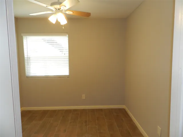 an empty room with a window and a fan