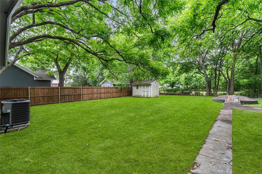 110 Hackberry Street Lancaster, TX 75146 - Photo 24 of 32 Spacious backyard featuring a manicured lawn, perimeter wood fencing, mature shade trees, a concrete walkway, and a storage shed