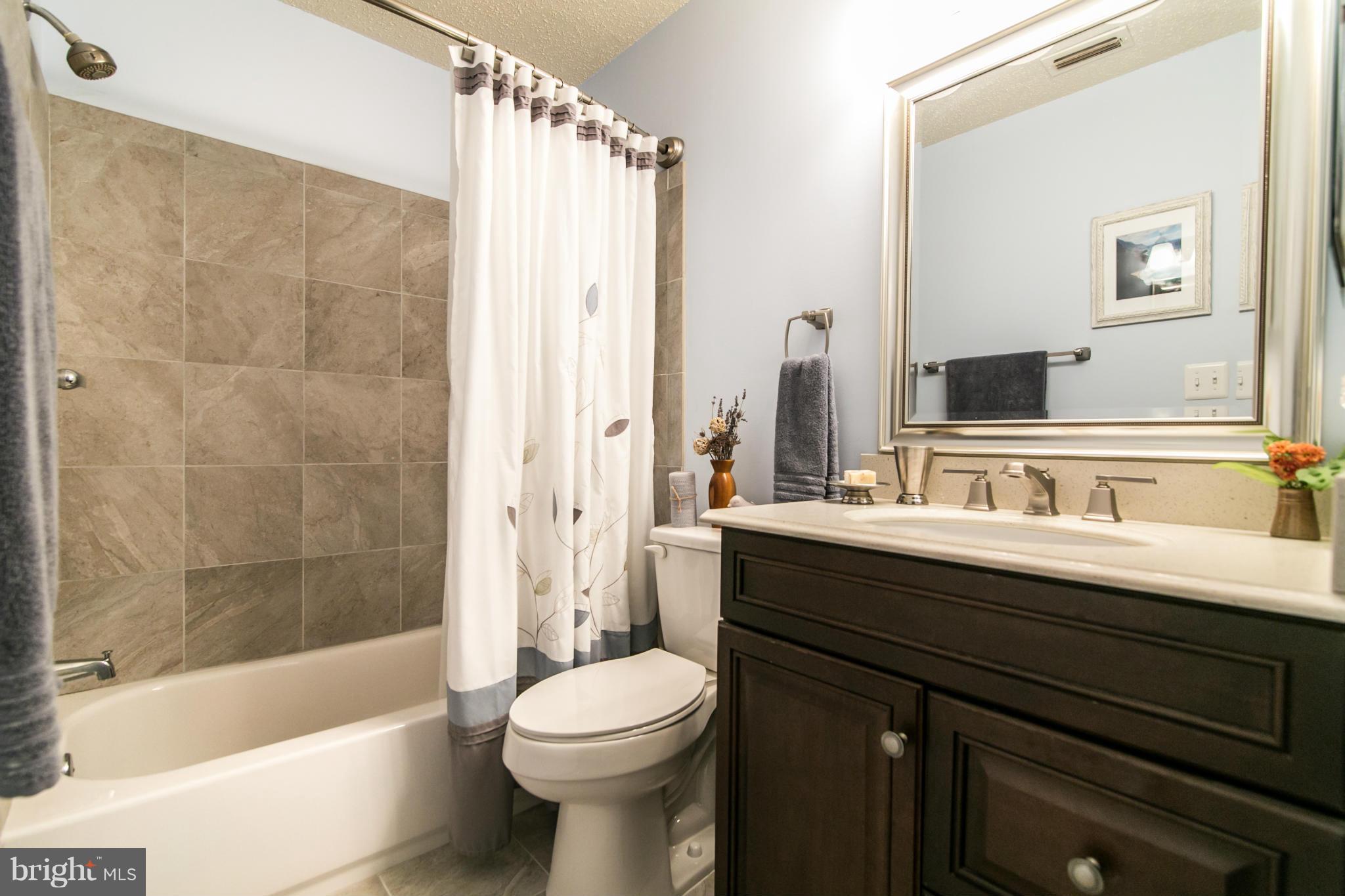 20951 Timber Ridge Terrace, Unit 101 Ashburn, VA 20147 - Photo 12 of 23 Master bath with quartz counters and ceramic tile.