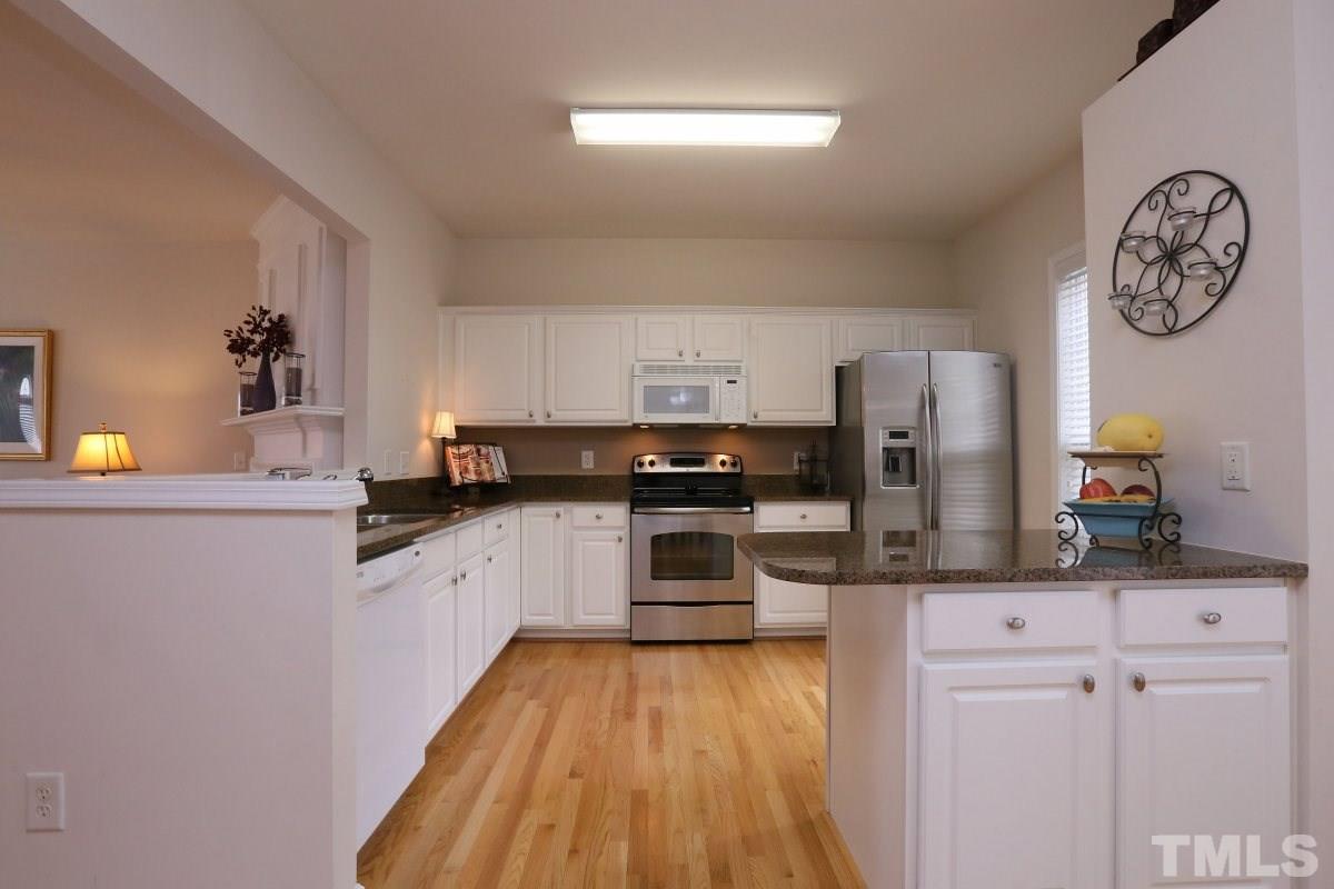 7113 Lovko Lane Raleigh, NC 27613 - Photo 2 of 25 a kitchen with granite countertop a refrigerator a stove a microwave and cabinets