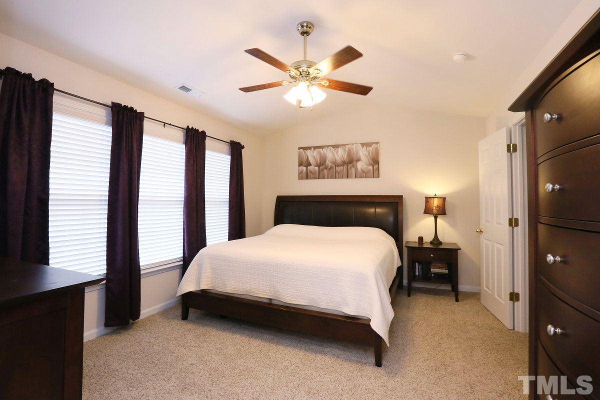 7113 Lovko Lane Raleigh, NC 27613 - Photo 13 of 25 a bedroom with a bed and a large window with a chandelier