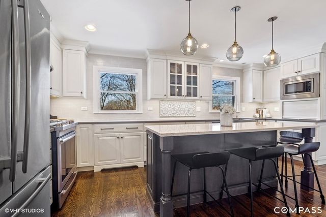 a kitchen with stainless steel appliances granite countertop a sink a stove a refrigerator cabinets and dining table with chairs