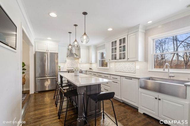 a kitchen with a sink a center island stainless steel appliances and cabinets