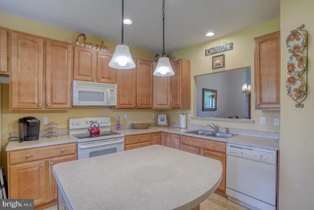 a kitchen with refrigerator a sink a stove and chairs