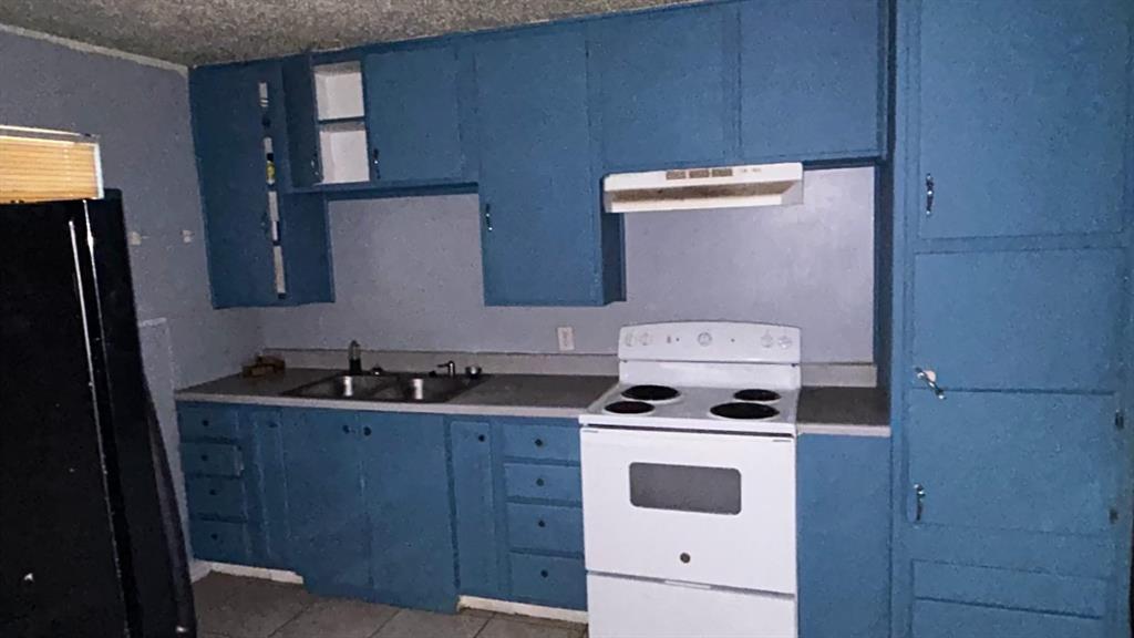508 Bremser Avenue, Unit 506 Killeen, TX 76541 - Photo 4 of 9 Kitchen featuring blue cabinetry, white range with electric cooktop, freestanding refrigerator, under cabinet range hood, and light tile patterned floors