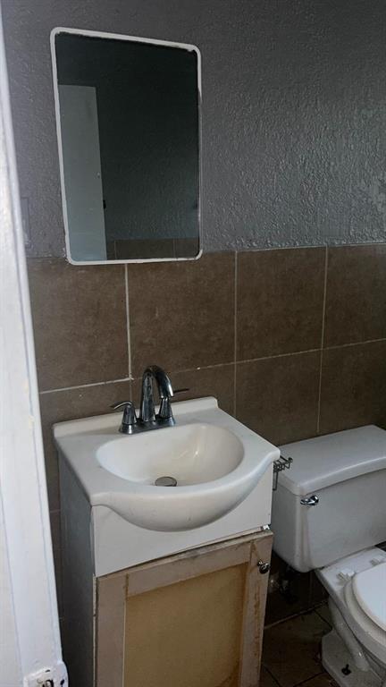 508 Bremser Avenue, Unit 506 Killeen, TX 76541 - Photo 7 of 9 Bathroom with vanity, a textured wall, tile walls, and a wainscoted wall