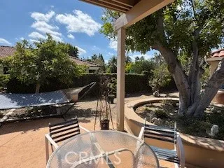 a roof deck with table and chairs a barbeque and a large trees with wooden fence