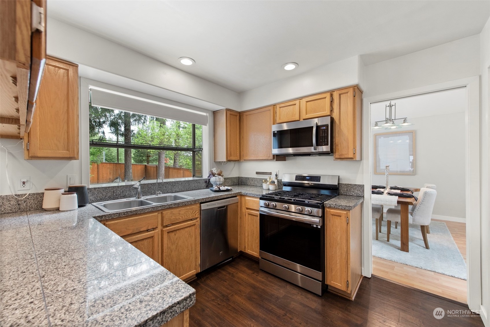 3545 252nd Place Southeast Sammamish, WA 98029 - Photo 11 of 31 a kitchen with stainless steel appliances granite countertop a stove top oven a sink dishwasher a microwave oven and a dining table with wooden floor