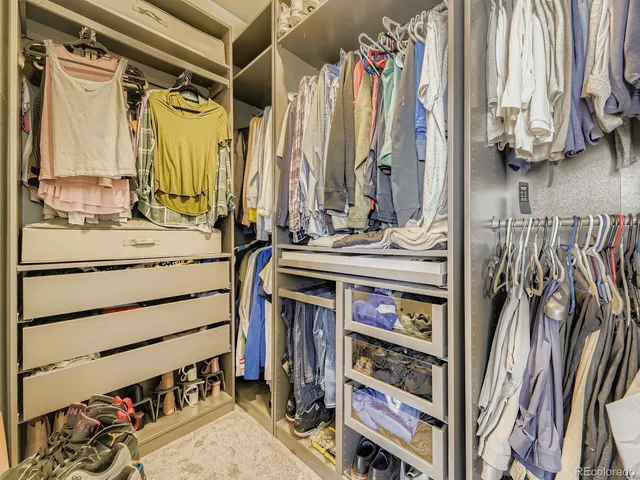 a view of walk in closet with clothes and shoes