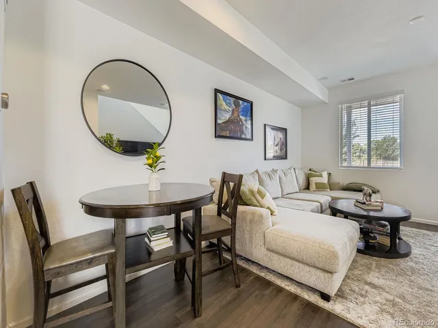 a living room with furniture a mirror and a wooden floor