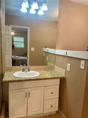 a bathroom with a granite countertop sink and a mirror