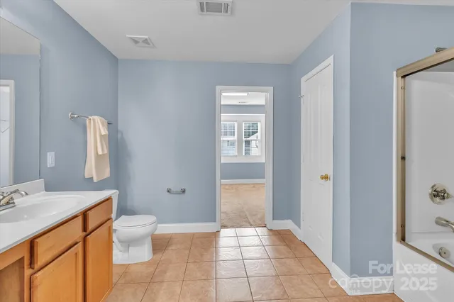 a spacious bathroom with a granite countertop sink a toilet and a mirror