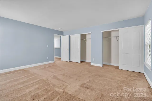a view of an empty room with closet and a window