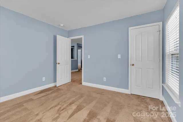 a view of an empty room with window and closet area