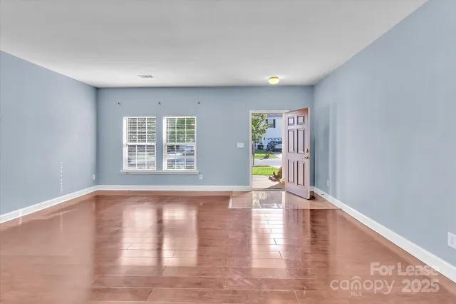 a view of an empty room with window and wooden floor