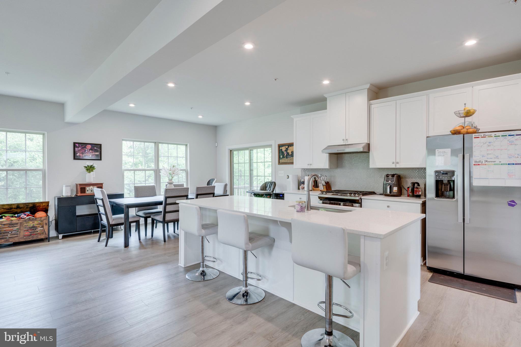 9004 Cavesson Way Upper Marlboro, MD 20772 - Photo 48 of 60 a kitchen with stainless steel appliances granite countertop a stove a sink a refrigerator a dining table and chairs with wooden floor