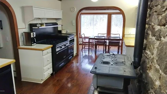 a kitchen with a stove a sink and wooden floor