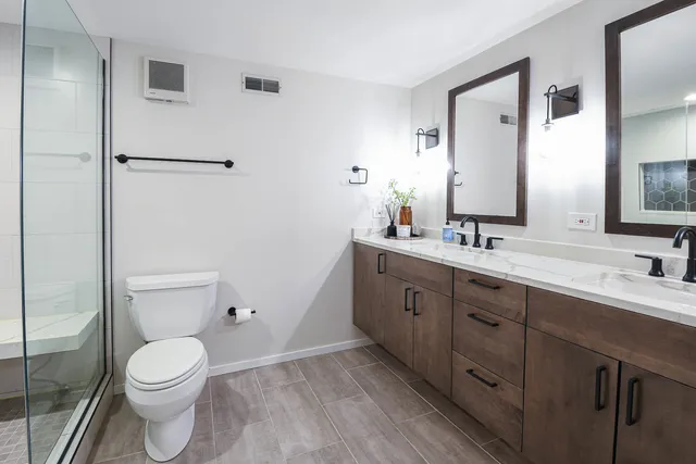 a bathroom with a toilet a sink a mirror and a shower