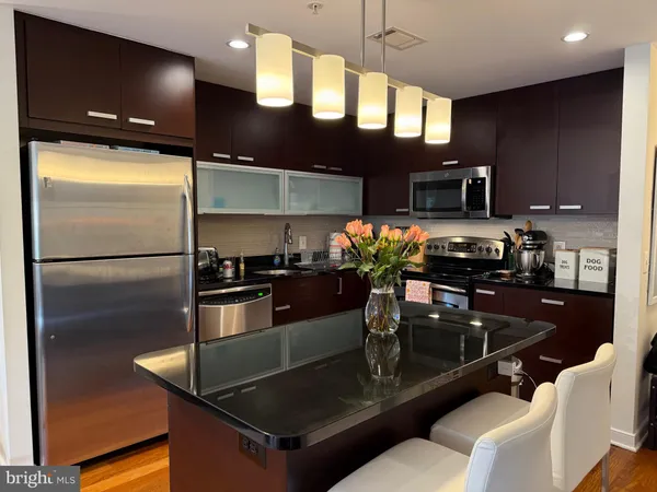 a kitchen with stainless steel appliances granite countertop a refrigerator a stove and a sink