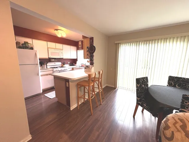 a open dining room with kitchen island wooden floor and a large window