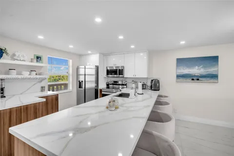 a large kitchen with kitchen island a large counter top stainless steel appliances and cabinets