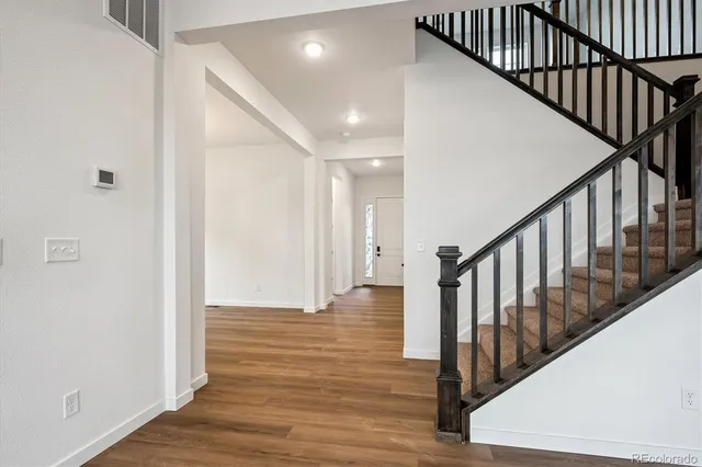 a view of a hallway with wooden floor and staircase