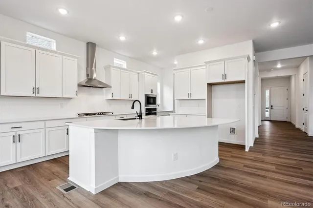 a large kitchen with stainless steel appliances granite countertop a white stove top oven and white cabinets