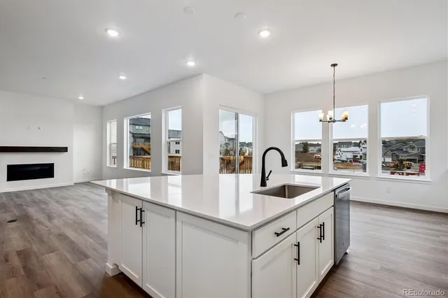 a kitchen with white cabinets a sink dishwasher and a stove with wooden floor