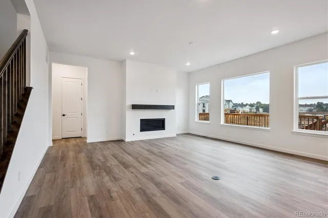 an empty room with large windows and fireplace
