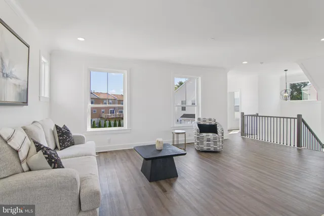 a living room with furniture a wooden floor and a kitchen view