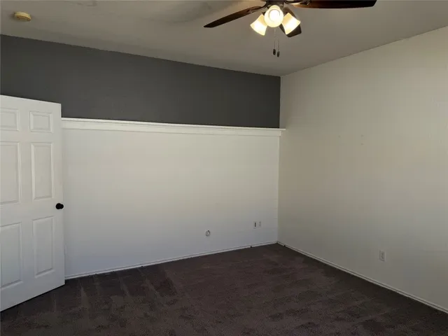 a view of an empty room with a chandelier fan