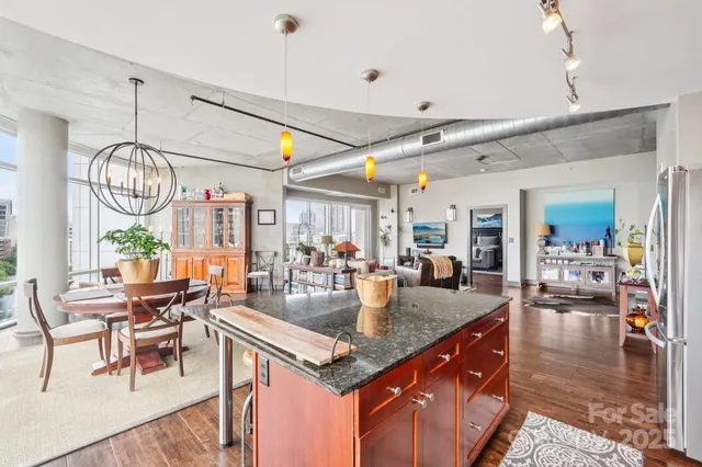 a kitchen with stainless steel appliances granite countertop a refrigerator a sink a stove and chairs with wooden floor