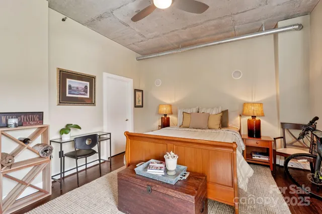 a bedroom with a bed and dresser with wooden floor