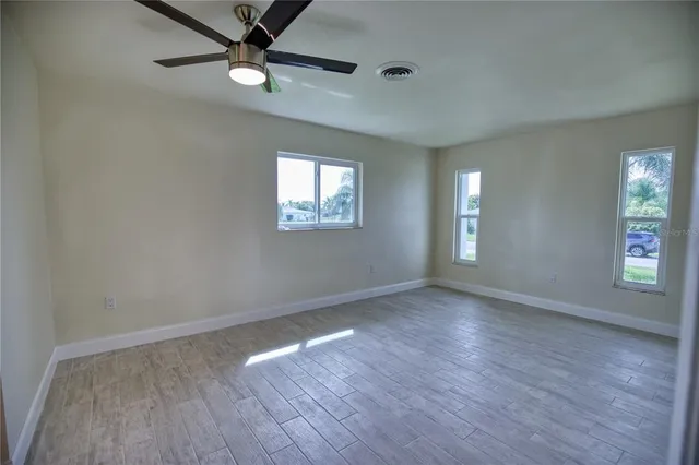 an empty room with wooden floor and windows