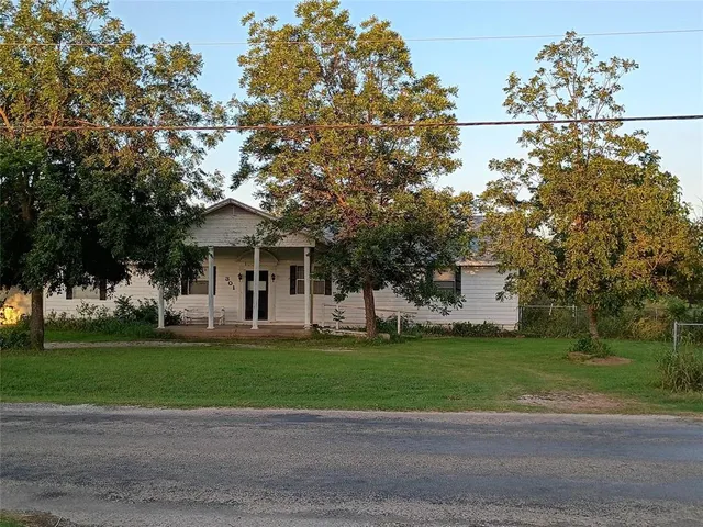 a front view of a house with a garden and trees