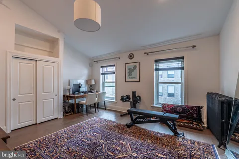 a bedroom with a bed and a computer on a desk next to a window