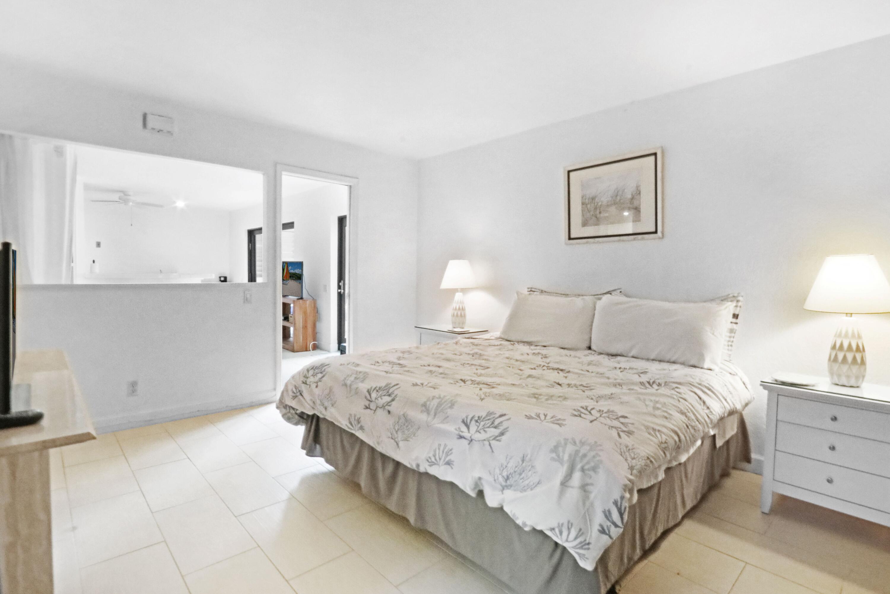 1605 Highway 1, Unit 4B Jupiter, FL 33477 - Photo 13 of 26 a spacious bedroom with a bed and a lamp