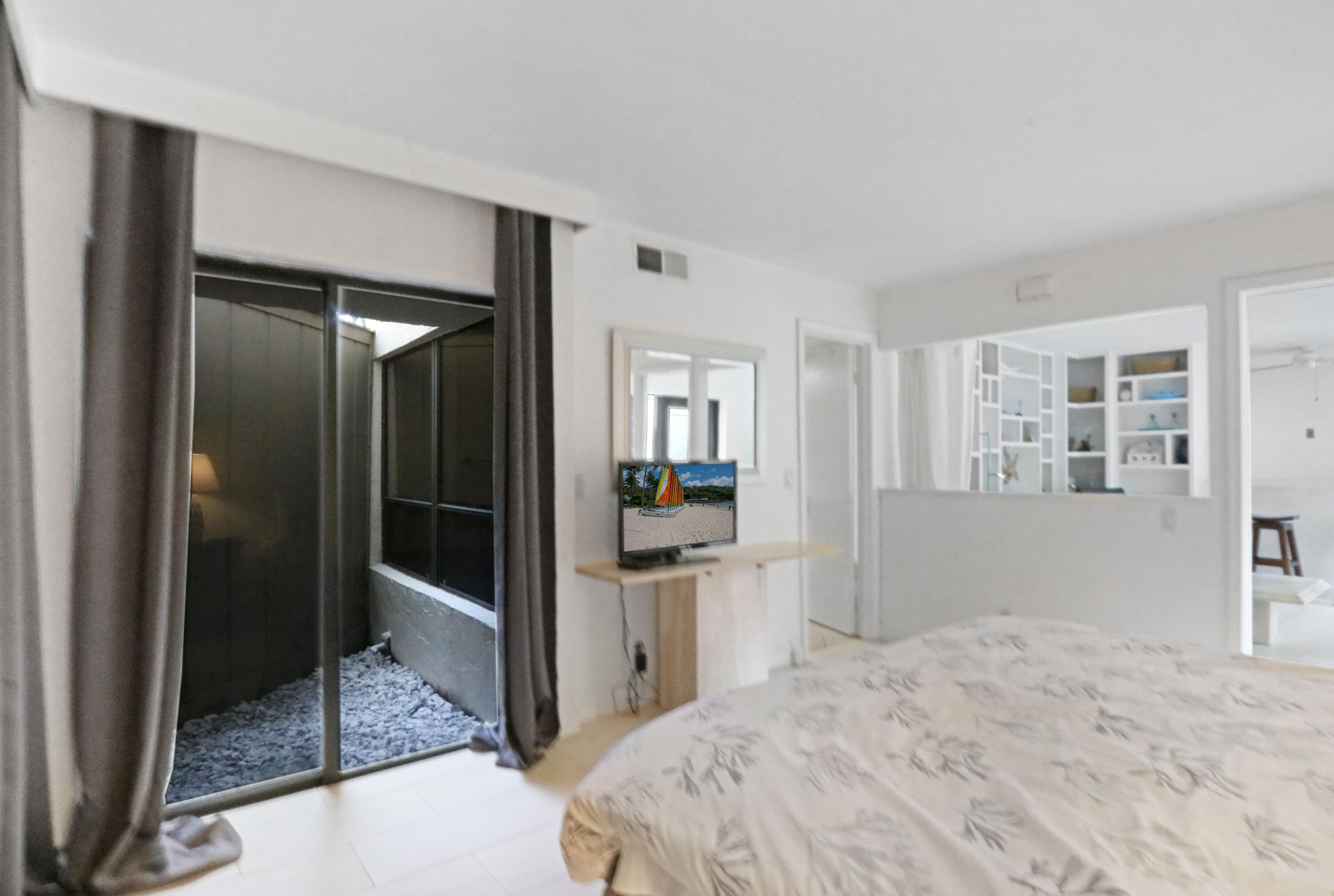 1605 Highway 1, Unit 4B Jupiter, FL 33477 - Photo 14 of 26 a bedroom with a bed and glass door