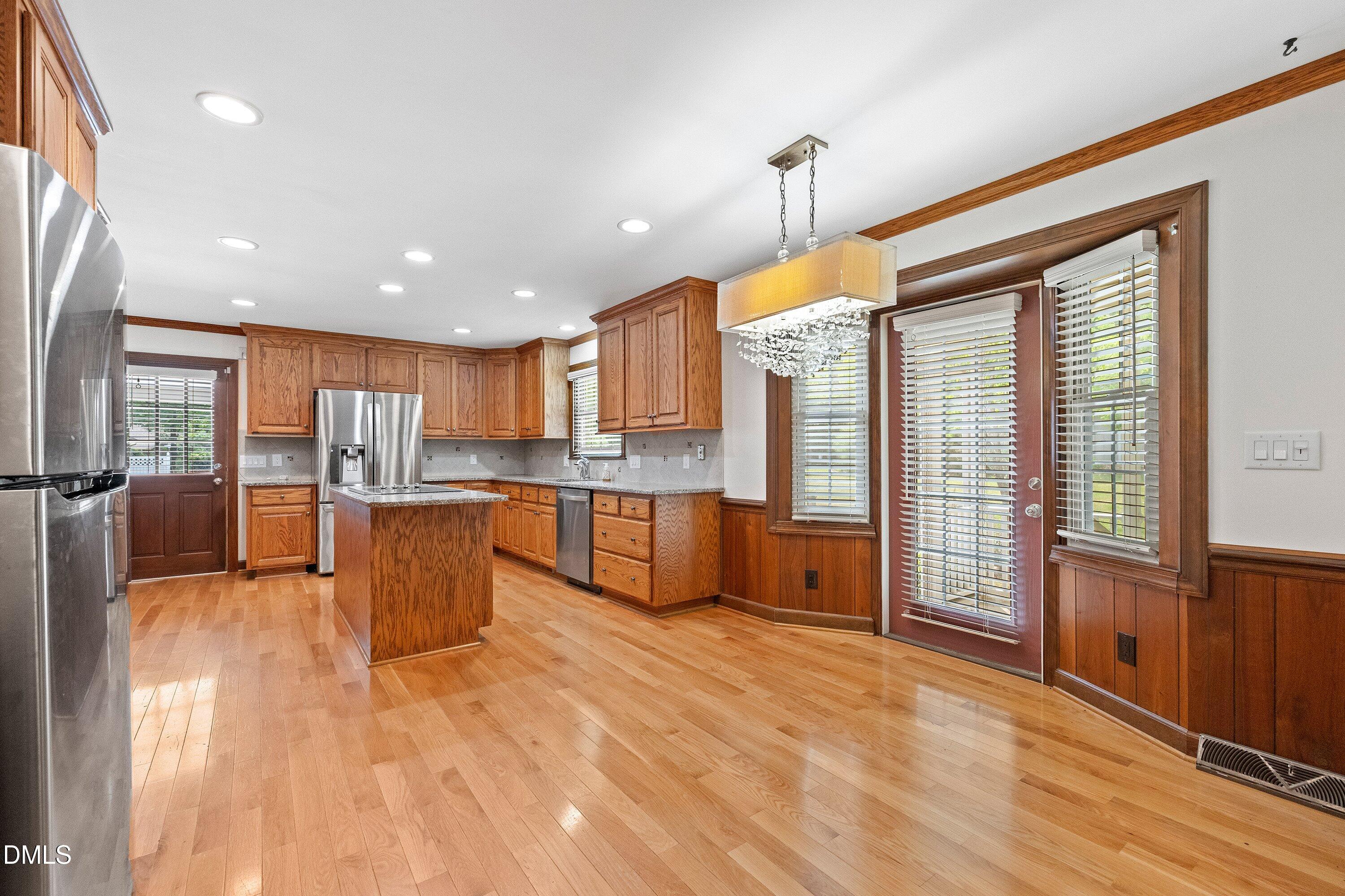 8133 Holly Forest Road Wake Forest, NC 27587 - Photo 13 of 50 a large kitchen with stainless steel appliances granite countertop a refrigerator a sink dishwasher a dining table and chairs with wooden floor