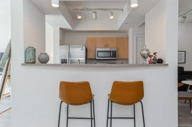 a kitchen with stainless steel appliances a dining table chairs microwave and sink