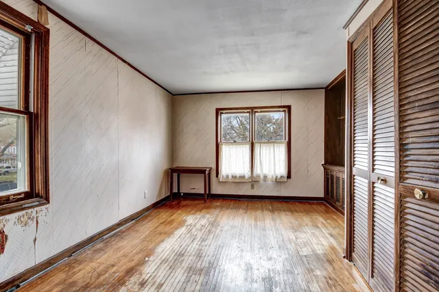an empty room with wooden floor and windows