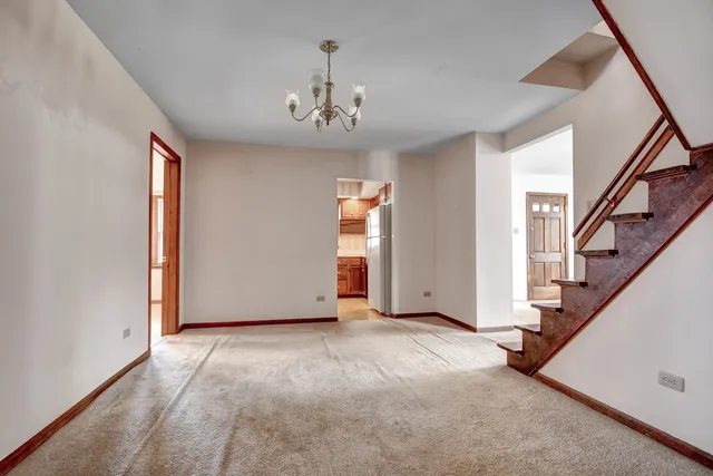 a view of an empty room with wooden floor and stairs