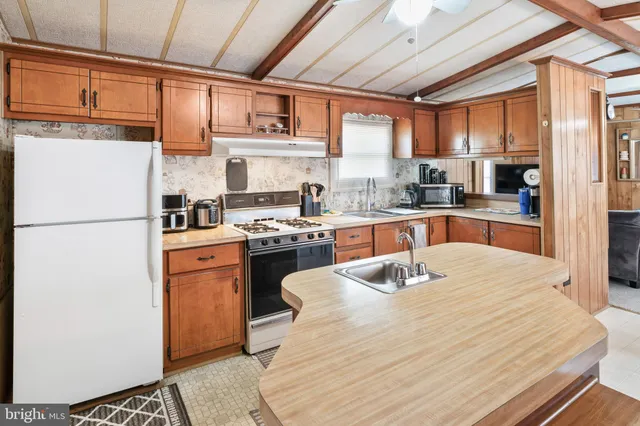 a kitchen with stainless steel appliances granite countertop a refrigerator a sink dishwasher a stove with wooden cabinets and floor