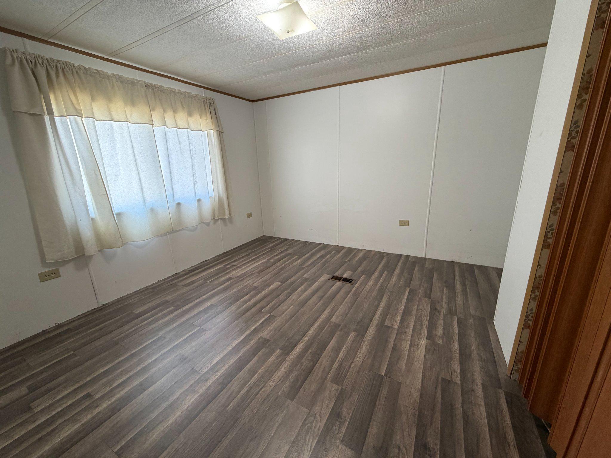 417 Captain Smith Lane Buena, NJ 08310 - Photo 17 of 25 an empty room with wooden floor and windows with curtains view