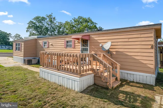 a view of a wooden house with a small yard and wooden fence