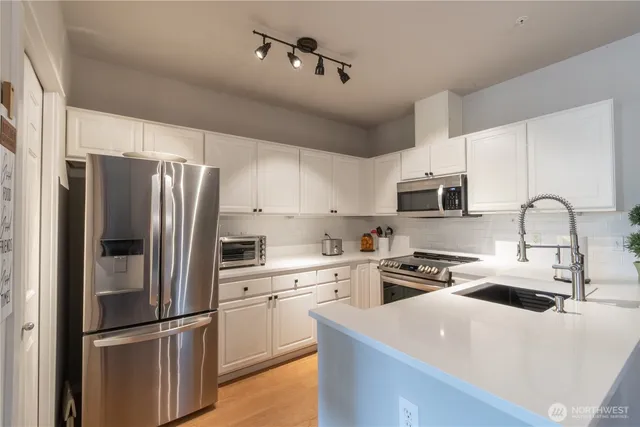 a kitchen with stainless steel appliances granite countertop a refrigerator sink and white cabinets